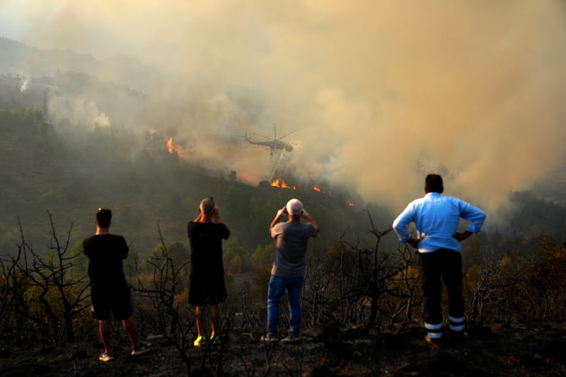 The fire has been bombarded with water by helicopter (AP)