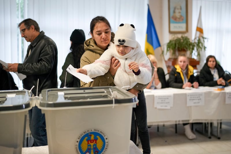 A woman holds a child as she casts her vote in Chisinau, Moldova (Vadim Ghirda/AP)