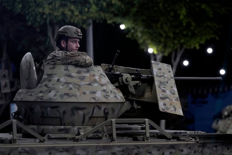 A Lebanese army soldier sits behind his weapon on the top of an armoured personnel carrier at the site of an Israeli airstrike in Beirut’s southern suburbs (Bilal Hussein/AP)