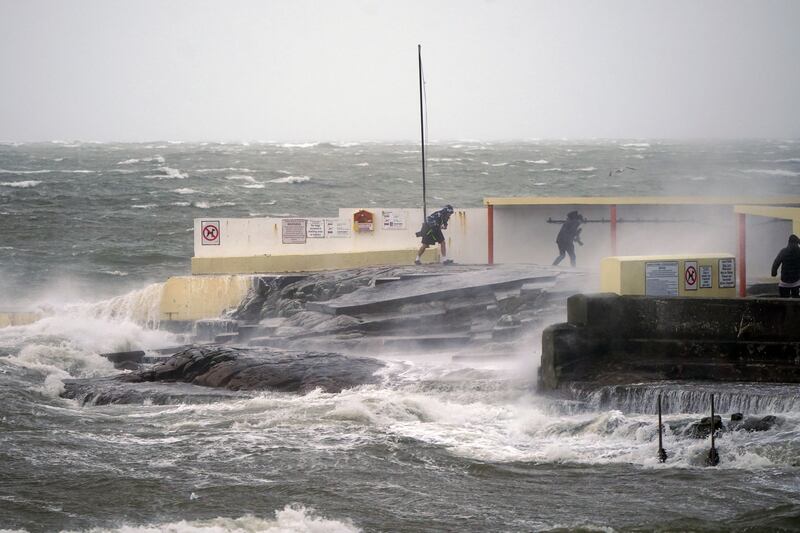 People walking away after taking photos of high waves at Salthill, Galway, during Storm Isha