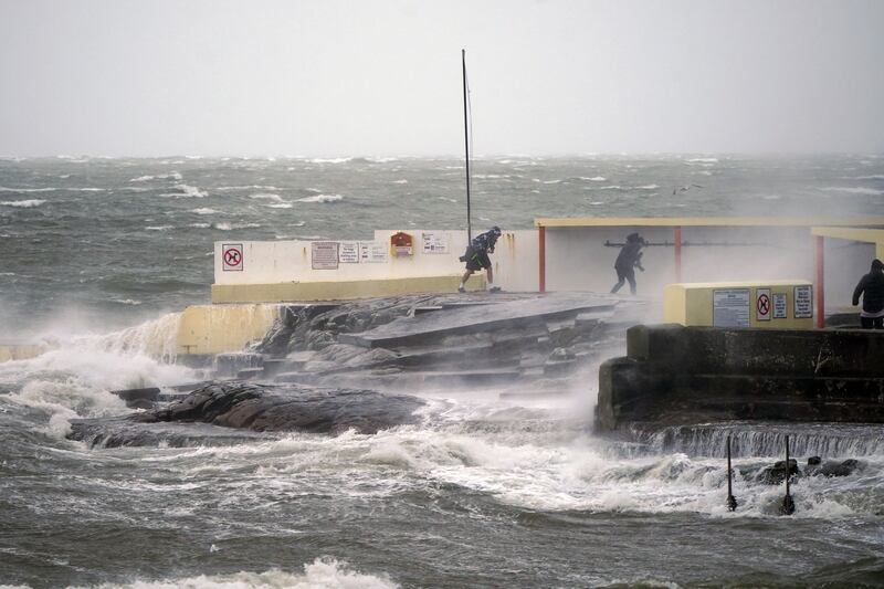 People take photos of high waves and leave at Salthill, Galway during Storm Isha