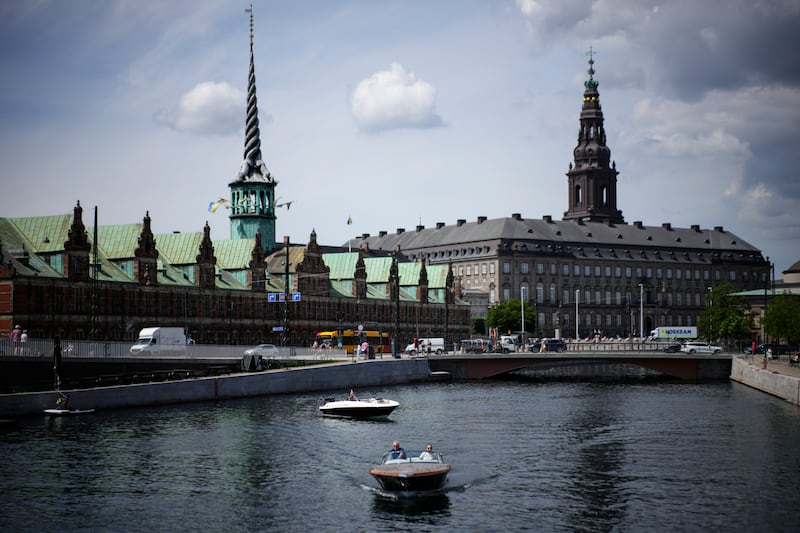 A boat on the Nyhavn river passes the Old Stock Exchange building in Copenhagen, Denmark (Daniel Cole/AP)