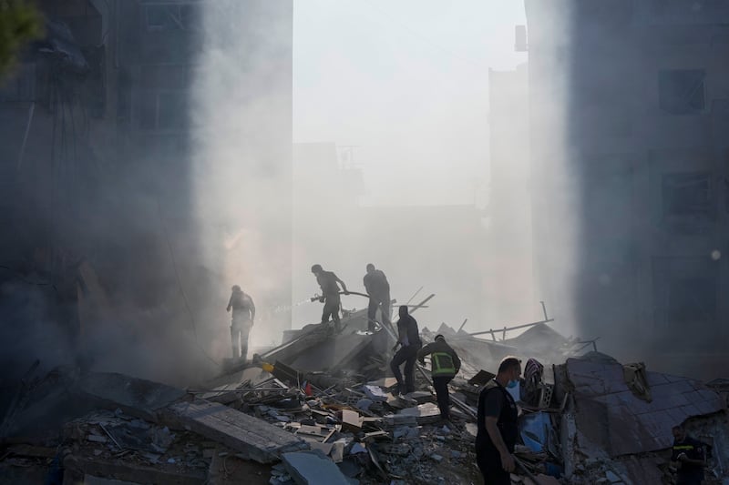 Civil defence workers extinguish a fire as smoke rises from the site of an Israeli airstrike in Tayouneh, Beirut (Hassan Ammar/AP)