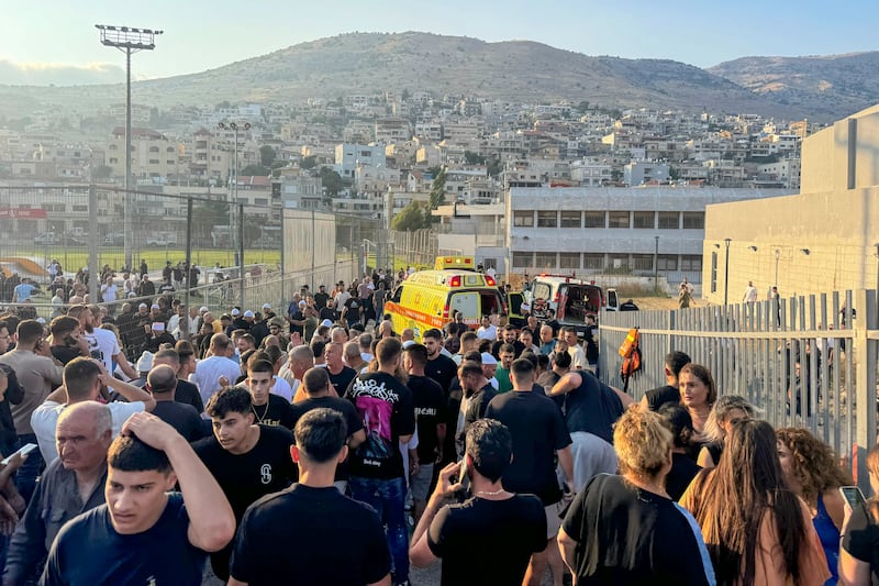 Residents and paramedics rushed to help children after a rocket hit a football field in the Golan Heights (Hassan Shams/AP)