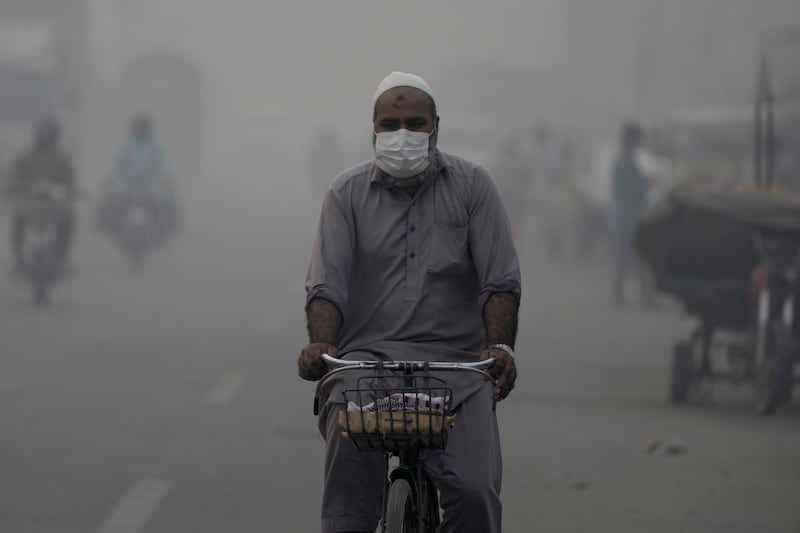 A cyclist, wearing a mask, heads to work amid the smog in Lahore (KM Chaudary/AP)