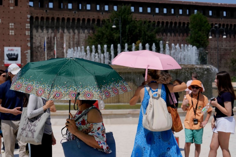 Tourists shelter from the sun in front of the Sforzesco Castle in Milan, Italy (AP Photo/Luca Bruno)