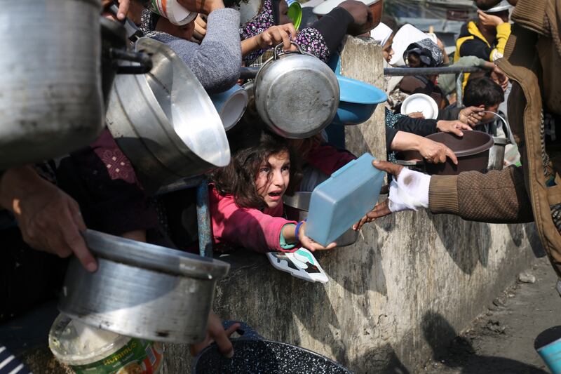 Palestinians line up for food during the ongoing Israeli air and ground offensive on the Gaza Strip in Rafah (Hatem Ali/AP)