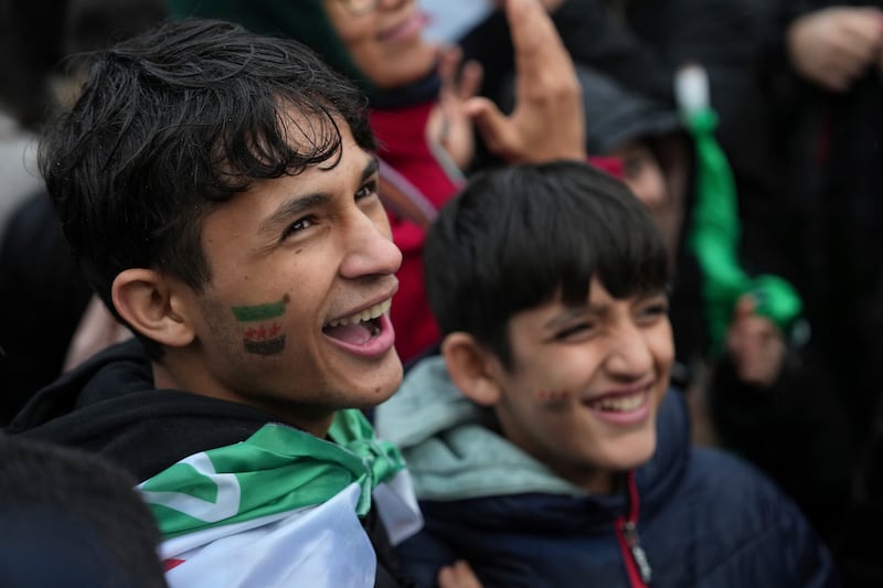 Young Syrians living in France smile during a rally on Republique square in Paris after the Syrian government fell in a stunning end to the 50-year rule of the Assad family (Aurelien Morissard/AP)