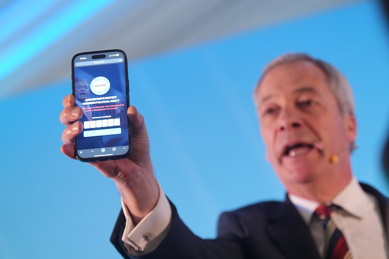 Reform UK leader Nigel Farage holding a phone displaying the number of Reform UK party members