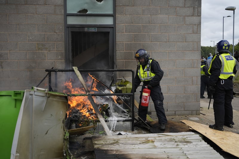 A fire is extinguished by police officers during the anti-immigration protest outside the Holiday Inn Express in Rotherham, South Yorkshire on August 4