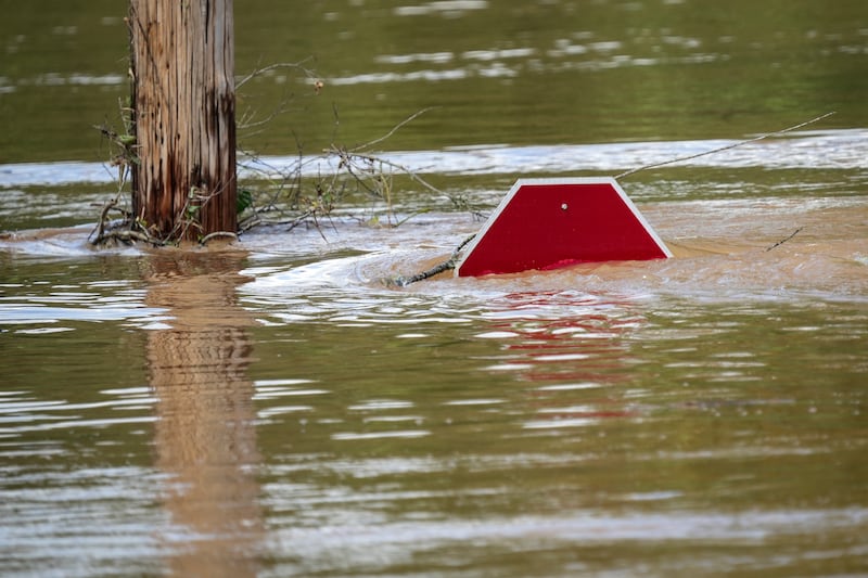 A stop sign can be barely seen above a flooded parking lot after torrential rain from Hurricane Helene caused severe flooding (AP Photo/Kathy Kmonicek)