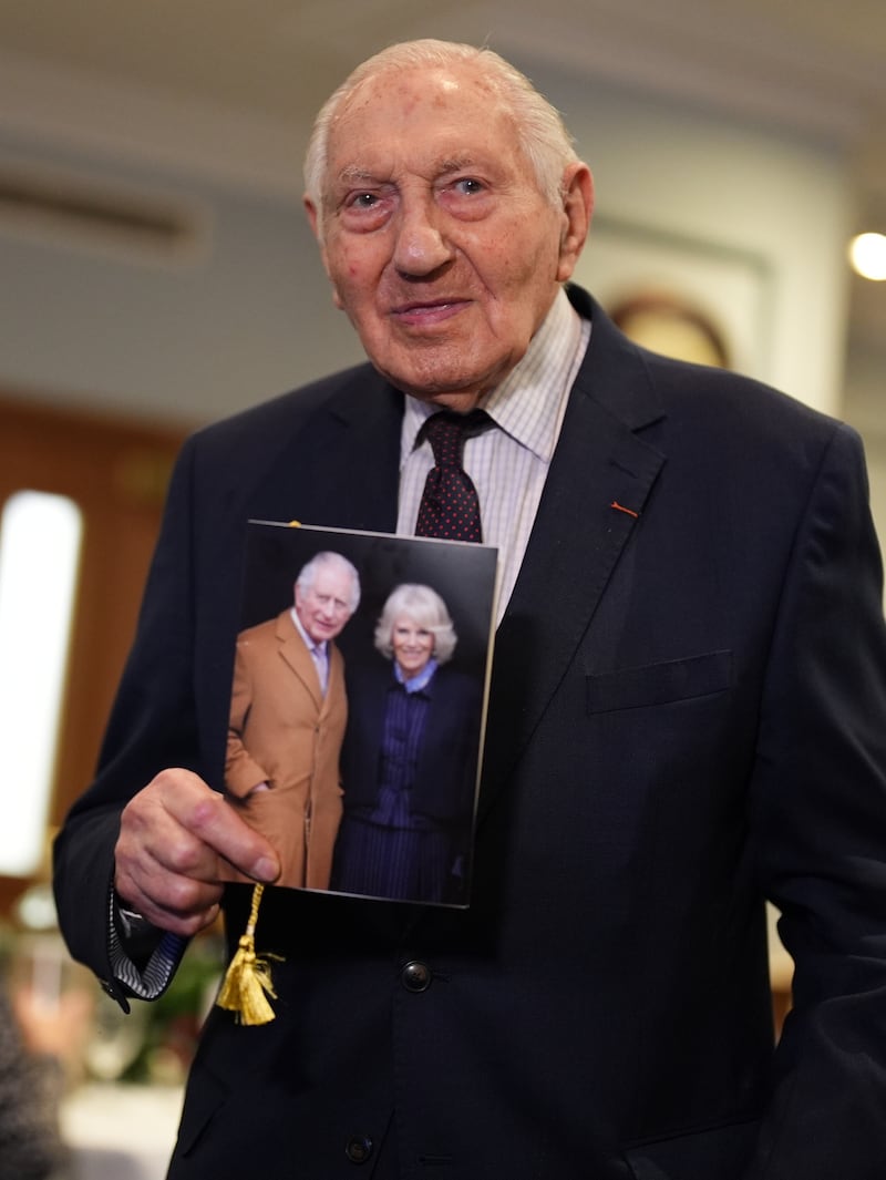 Normandy veteran Mervyn Kersh holds his card from the King and Queen during a surprise party for his 100th birthday