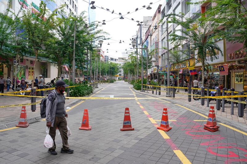 A man crosses a closed roadside after another deep sinkhole appeared a week after a woman fell into a sinkhole when a sidewalk caved in in Kuala Lumpur (Vincent Thian/AP)