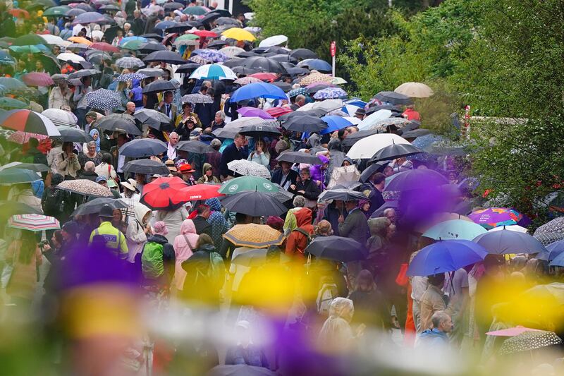 Guests shelter under umbrellas as it rains during the RHS Chelsea Flower Show on Tuesday