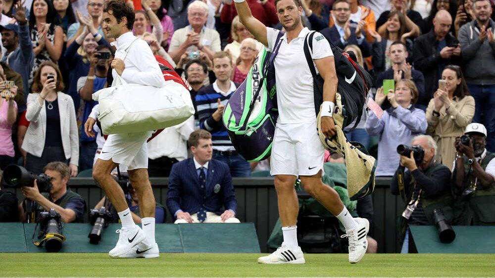 Marcus Willis waves as he leaves centre court with Roger Federer following his defeat at Wimbledon on Wednesday