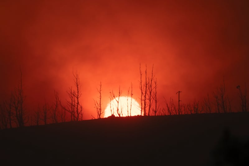 The sun sets behind burned trees in Varnava village during a wildfire (Michael Varaklas/AP)