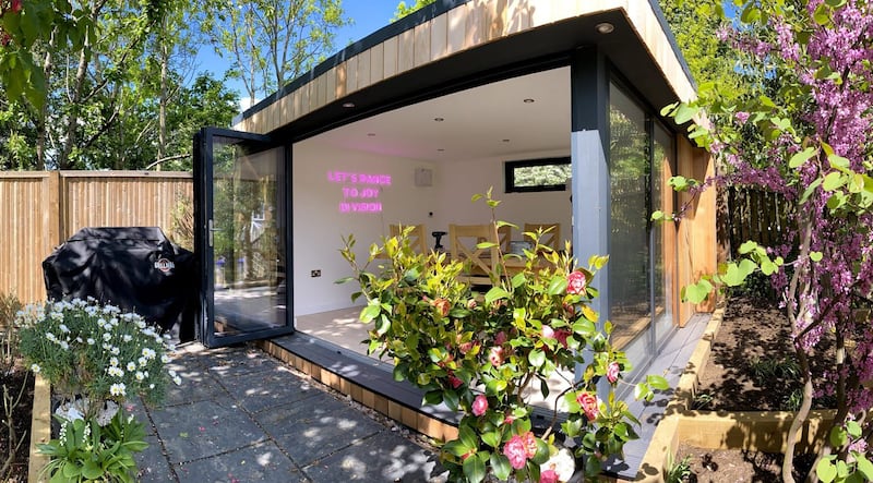 Garden room with entertaining space in elevated garden, with bifold doors opening to decked area
