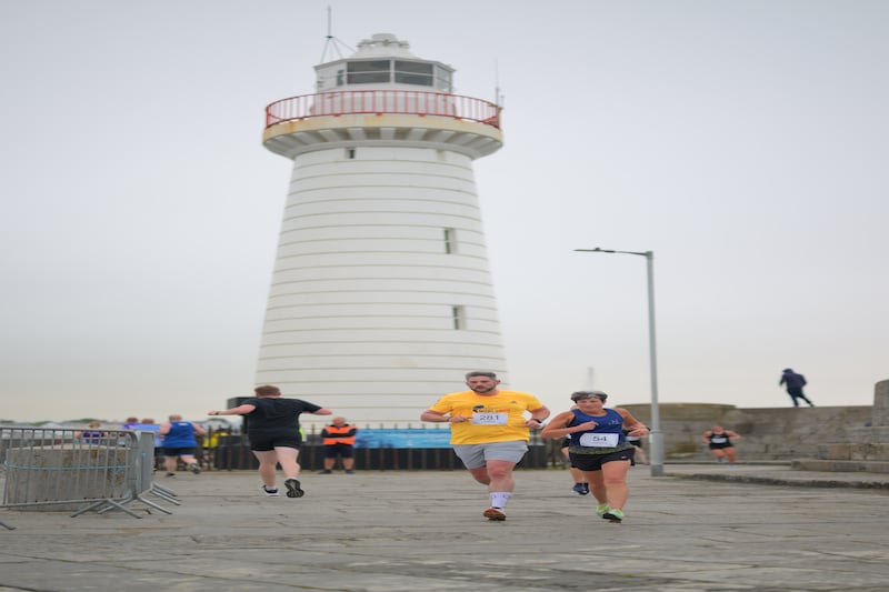 Group of runners in 5k race in front of white lighthouse