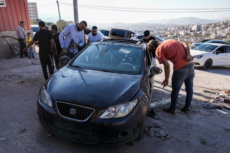 Palestinians look at a damaged car following an Israeli airstrike in Tubas, West Bank (Majdi Mohammed/AP)