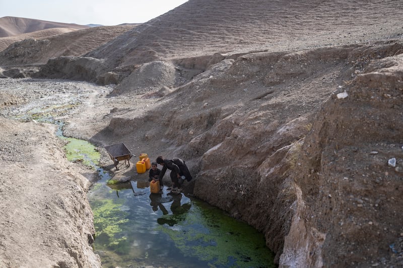 Two brothers fill canisters with water from a stagnant pool about two miles from their home in Kamar Kalagh village outside Herat, Afghanistan (Petros Giannakouris/AP)