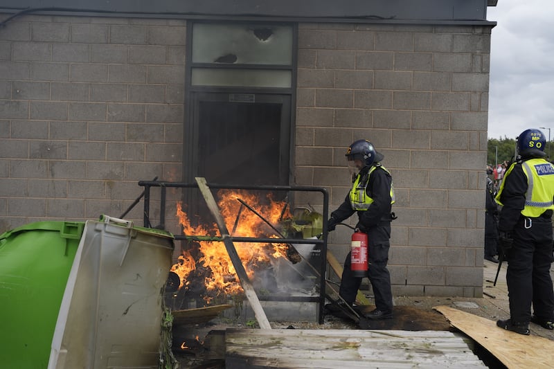 A fire is extinguished by police officers during the disorder outside the Holiday Inn Express in Manvers, near Rotherham, on August 4 2024