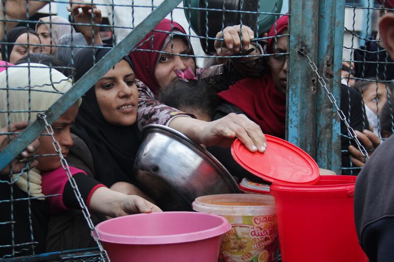 Palestinians line up to receive meals at Jabaliya refugee camp in the Gaza Strip (Mahmoud Essa/AP)