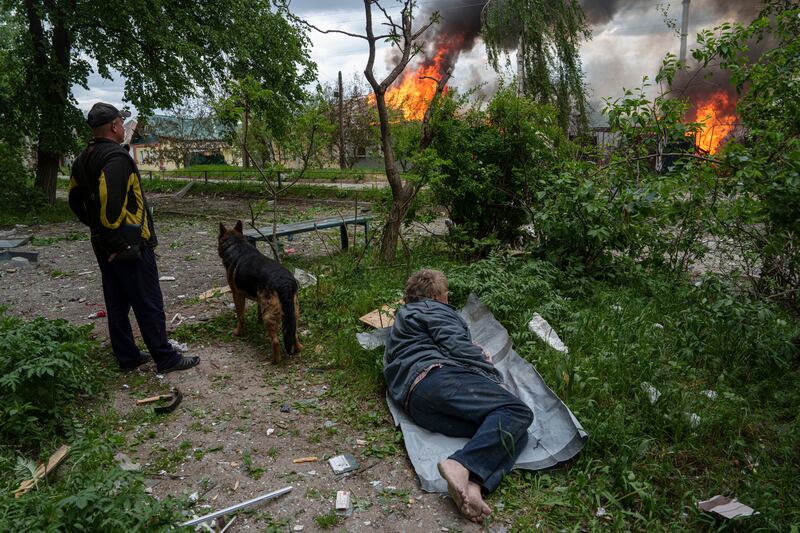 A man lies on the ground as he watches his burning house destroyed by a Russian air strike in Vovchansk, Ukraine (Evgeniy Maloletka/AP)