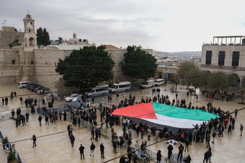 People hold a giant Palestinian flag in Manger Square (AP)