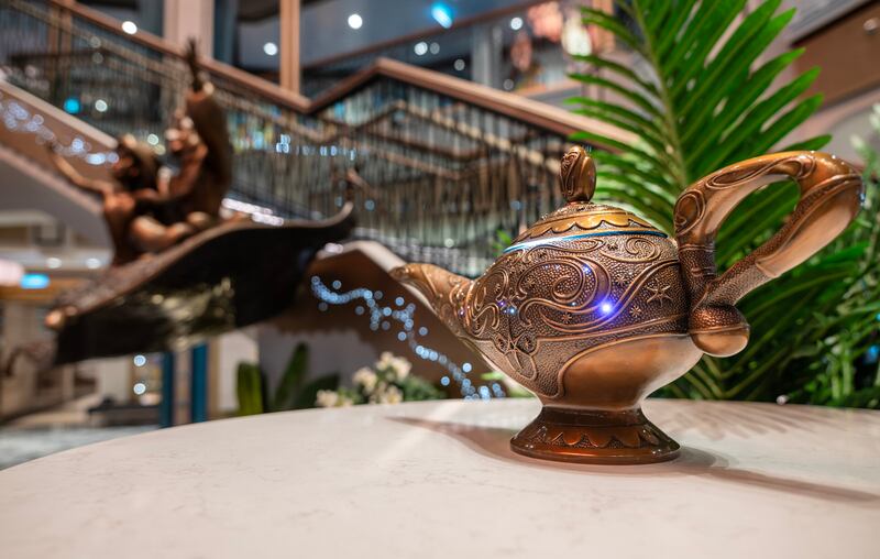 Genie’s Lamp lights up by the bronze statue of Aladdin and Princess Jasmine in the Grand Hall of the Disney Treasure