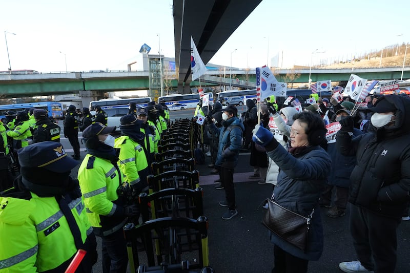 Supporters of impeached South Korean President Yoon Suk Yeol stage a rally to oppose a court having issued a warrant to detain him as police officers stand guard (Lee Jin-man/AP)