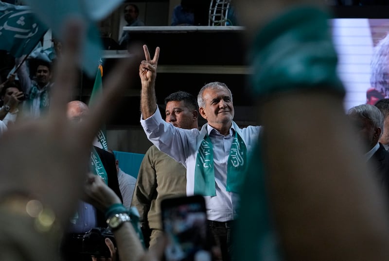 Iranian presidential candidate Masoud Pezeshkian and his supporters flash the victory sign during a campaign stop in Tehran (Vahid Salemi/AP)