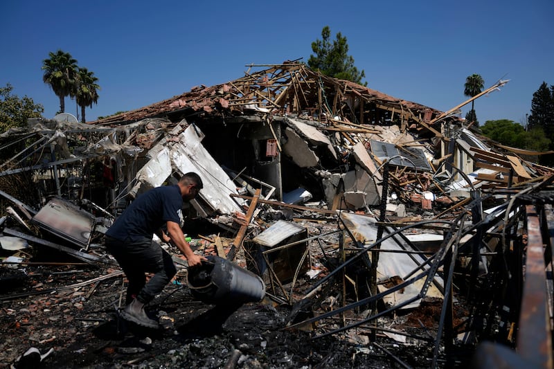 A man works next to a destroyed home after rockets struck in Katzrin, in the Israeli-annexed Golan Heights (Ariel Schalit/AP)