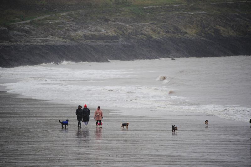 People walking on the beach in Barry Island, in the Vale of Glamorgan, South Wales, as wind, rain and snow warnings are in force across parts of the UK