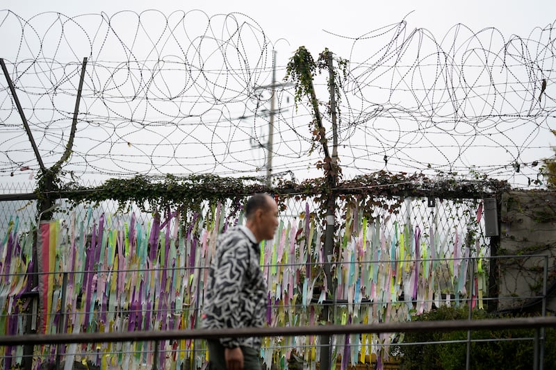 A visitor walks near a wire fence decorated with ribbons written with messages wishing for the reunification of the two Koreas at the Imjingak Pavilion in Paju, South Korea (Lee Jin-man/AP)