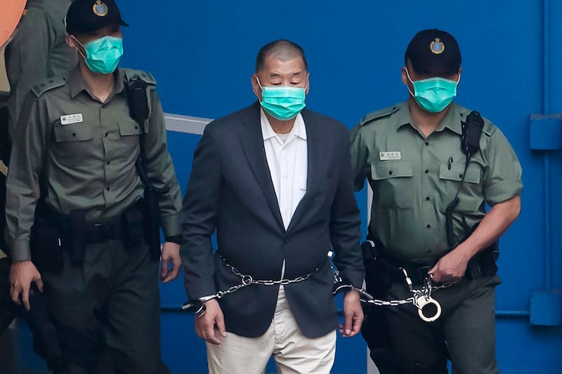 Jimmy Lai, centre, who founded the Apple Daily tabloid, is escorted by Correctional Services officers to get on a prison van (AP Photo/Kin Cheung)