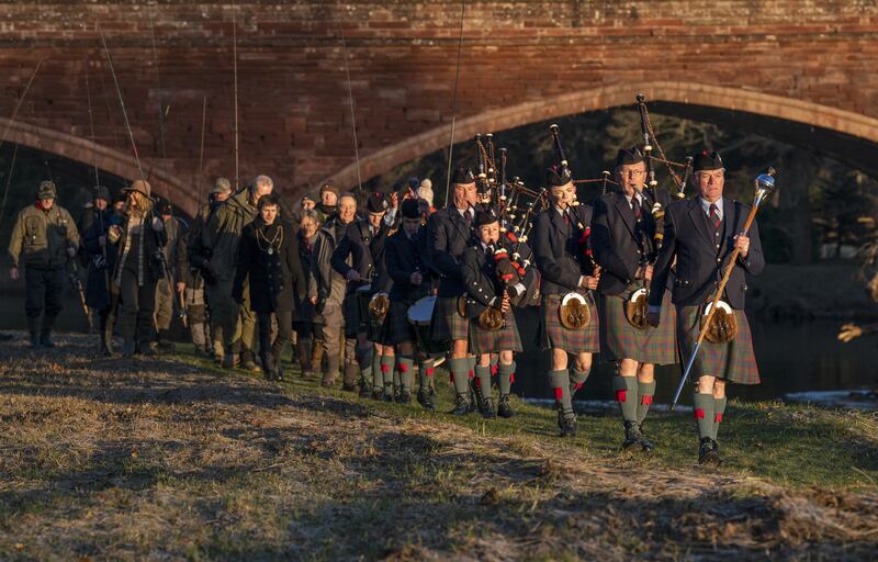 The Perth and District Pipe Band lead the anglers in a procession along the bank of the River Tay on the opening day of the salmon fishing season