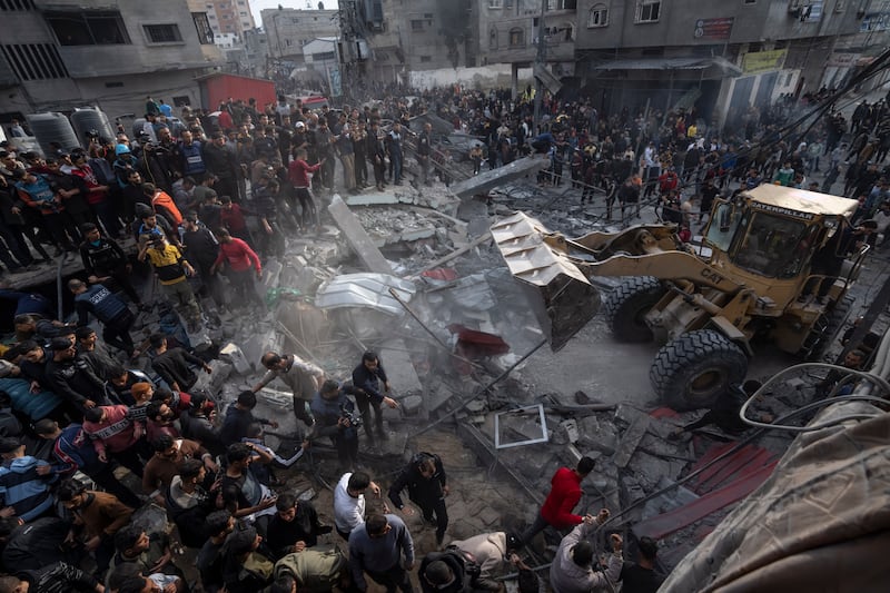 Palestinians search for bodies and survivors in the rubble of a residential building destroyed by an Israeli airstrike, in December (Fatima Shbair/AP)