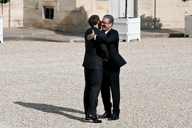 Prime Minister Sir Keir Starmer is embraced by French President Emmanuel Macron at the Elysee Palace