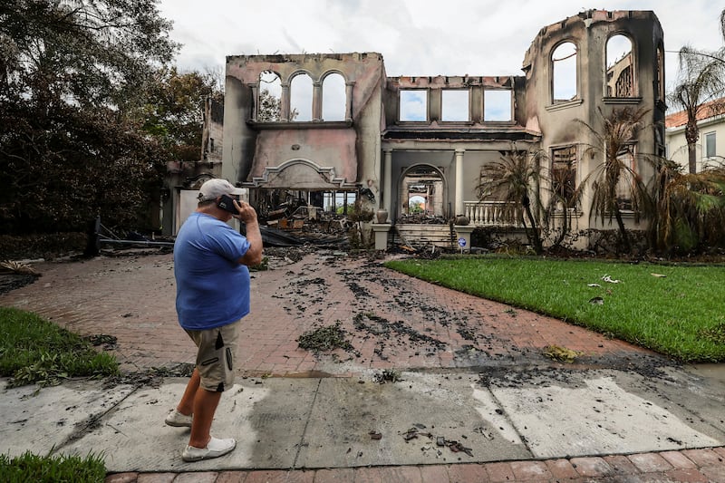 Joe Daum looks at the remains of a friend’s home that burned during Hurricane Helene on Davis Island, Tampa, Florida