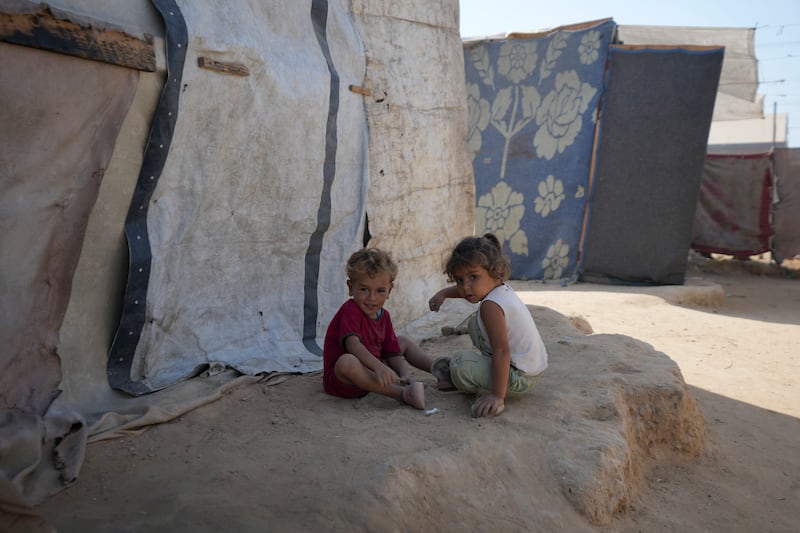 Displaced Palestinian children sit next to their tent in Deir al-Balah in the Gaza Strip (Abdel Kareem Hana/AP)