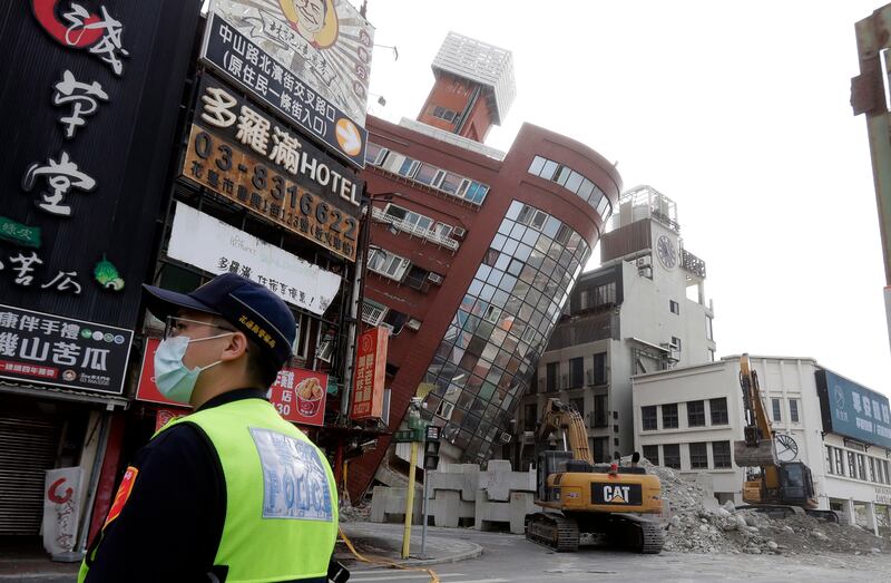A police officer stands guard near a partially collapsed building a day after a powerful earthquake struck in Hualien (Chiang Ying-ying/AP)