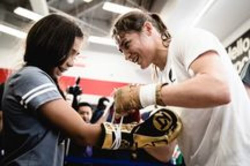 Katie Taylor laces her gloves on a young fan