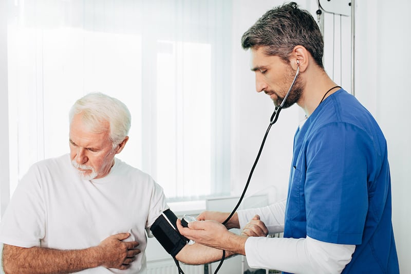 Young male GP measuring the blood pressure of an elderly man