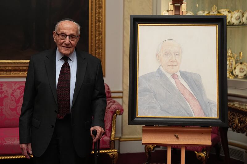 Holocaust survivor Manfred Goldberg poses beside a portrait of himself during a reception marking Holocaust Memorial Day at Buckingham Palace