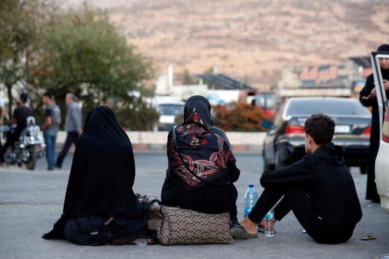 Lebanese people fleeing the Israeli bombardment, wait after crossing into Syria at the Syrian-Lebanese border crossing in Jdaidet Yabous (Omar Sanadiki/AP)