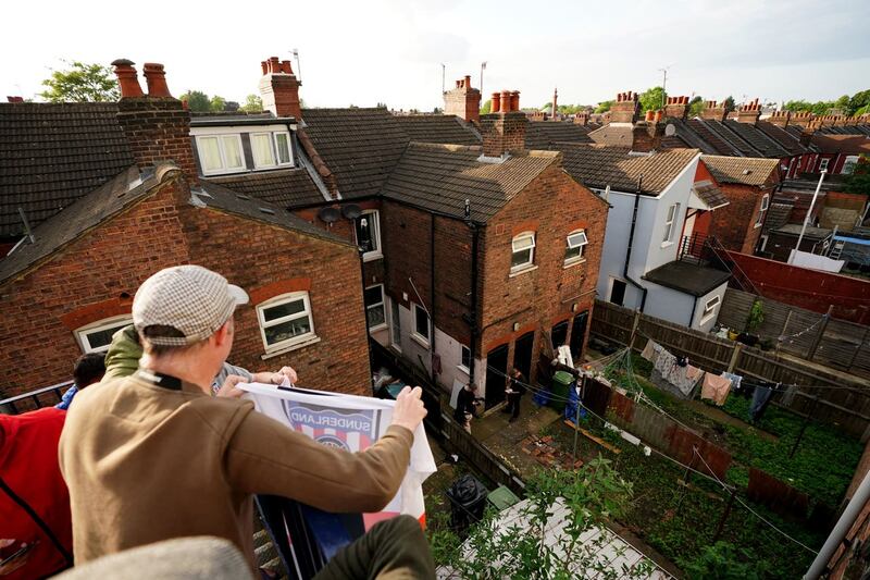 Sunderland fans gesture to residents in a garden next to Kenilworth Road 