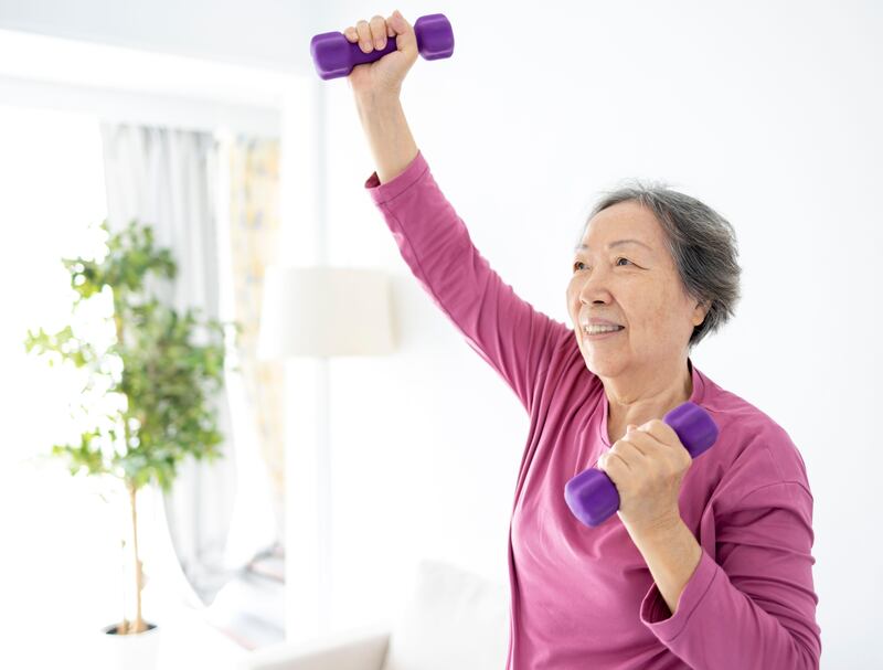 Senior woman doing exercises with dumbbells indoors