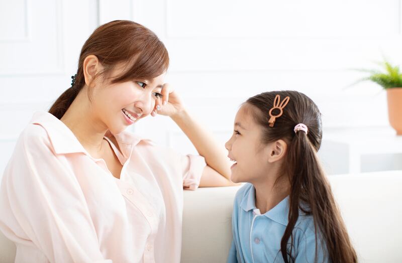 Mother chatting to her young daughter on the sofa at home