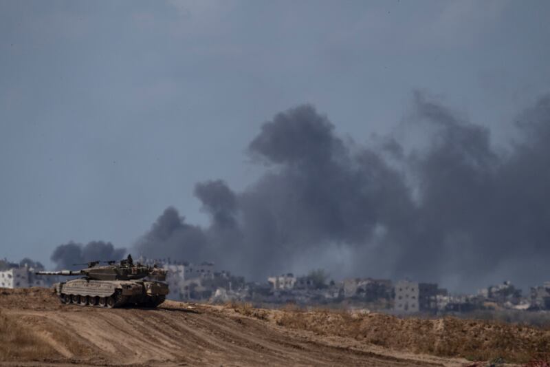 Backdropped by smoke rising to the sky after an explosion in the Gaza Strip, an Israeli tank stands near the Israel-Gaza border as seen from southern Israel (Leo Correa/AP)