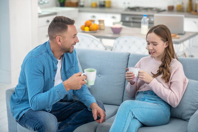 Dad and daughter smiling and chatting on the sofa